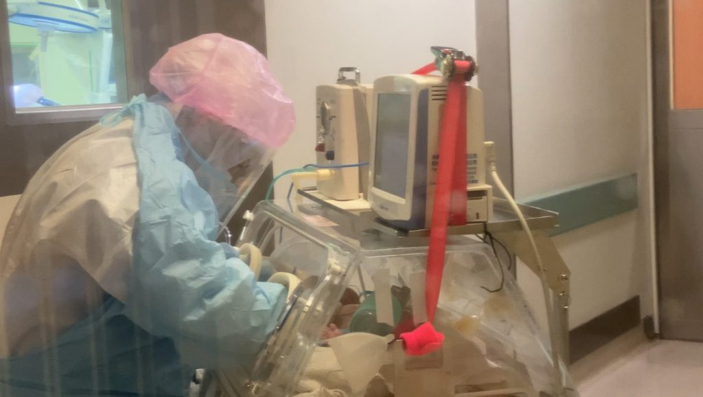 新生兒科醫護人員穿戴防護裝備照顧保溫箱裡的寶寶。圖片來源／台北慈濟醫院