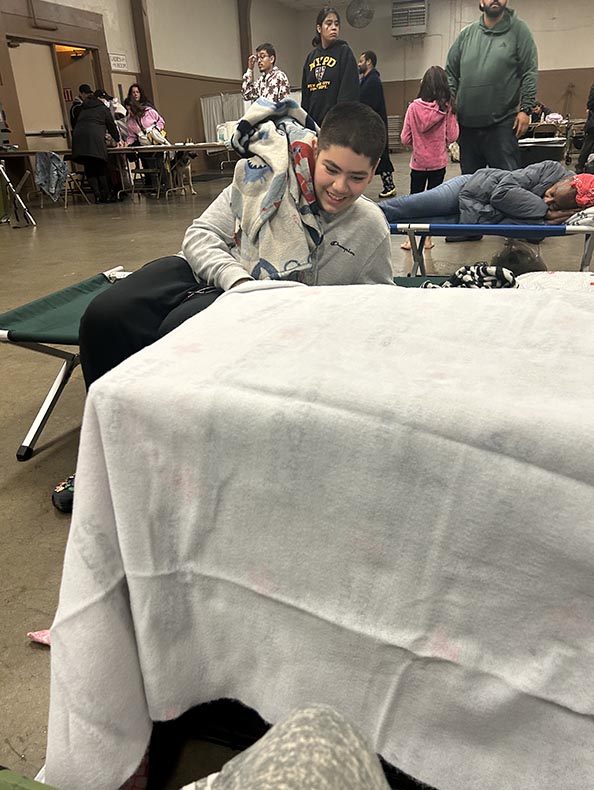 Mercedes Perez’s oldest child, who is autistic, settles in at the Red Cross shelter after the family evacuates on the night of the flooding. Photo/Mercedes Perez