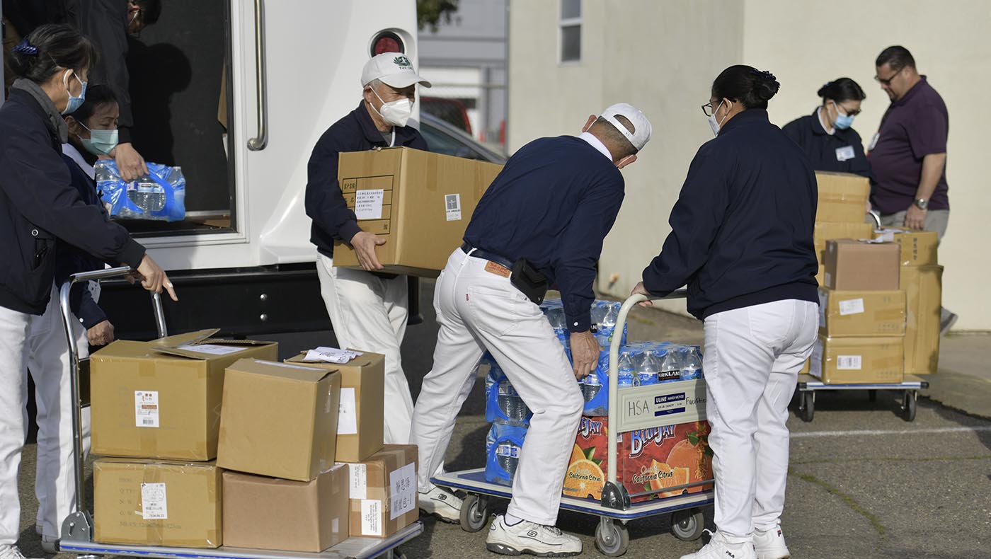 The Tzu Chi USA Northwest Region volunteer team unloads blankets and other supplies after arriving at the FEMA Disaster Relief Center in Merced County on February 4, 2023. Photo/C. M. Yung