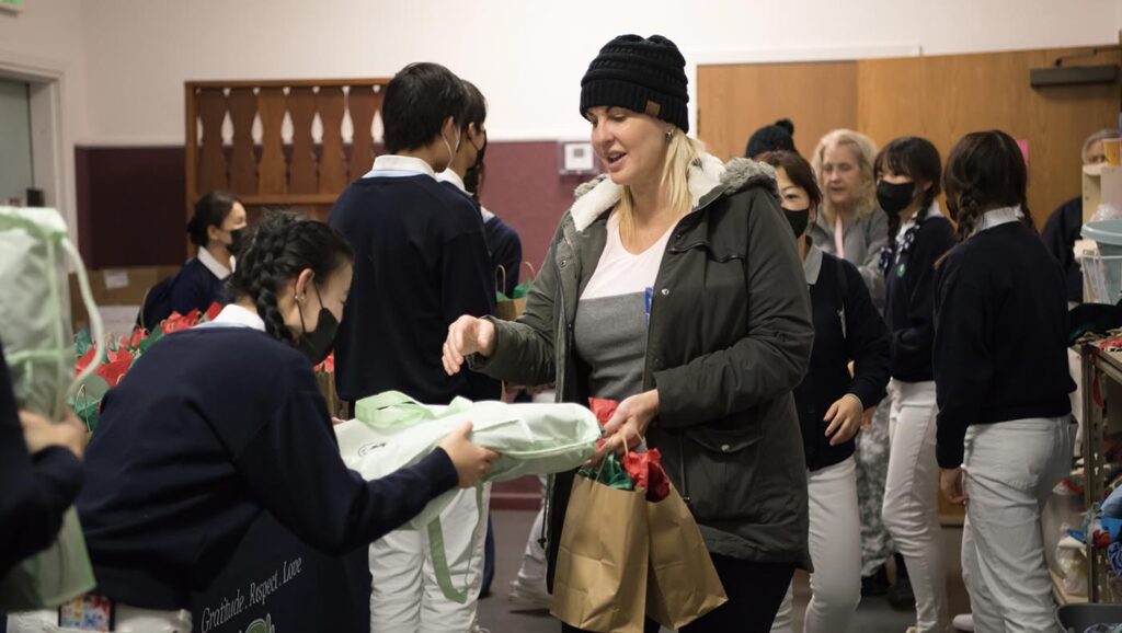 Tzu Chi Youth Group volunteers offer gift bags to guests at the “Moving Forward Holiday Celebration” at the Magalia Community Church. Photo/Min Yung Cheung