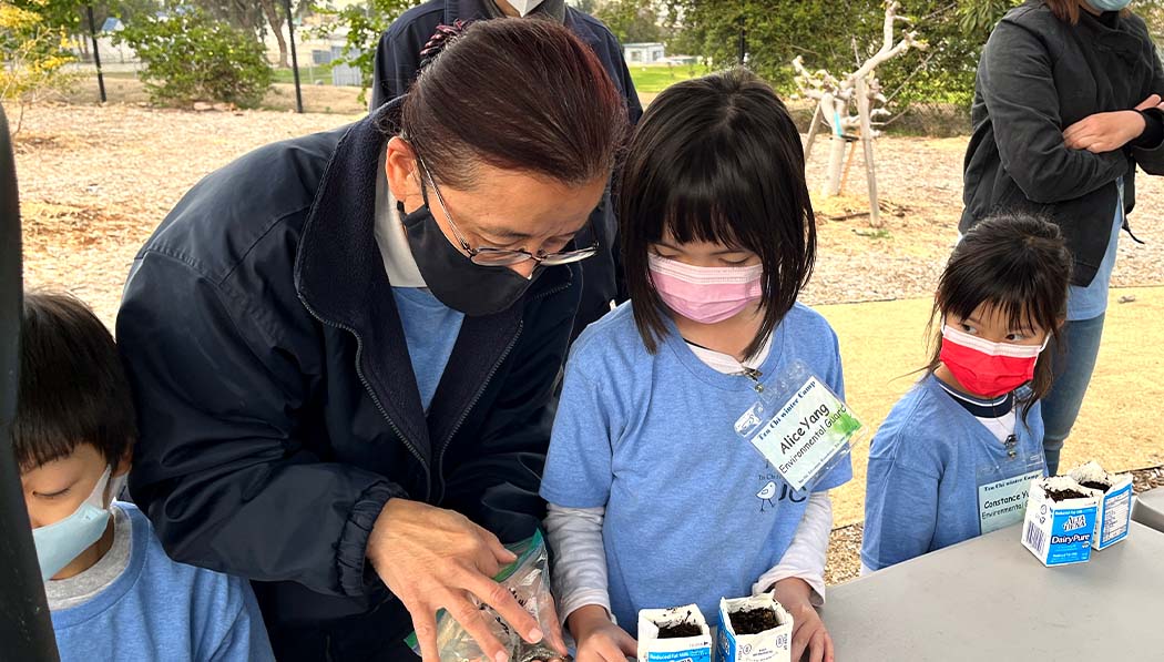 Tzu Chi volunteer teaching children how to plant in a milk box