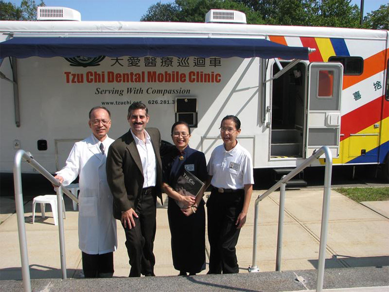 County Commissioner Steve Levy (second left), then convenor of TIMA Long Island, Dr. Richard Huang (left), then Long Island Branch Office director Joan Sung (second right), and dental surgeon Dr. Hueiju Lin of TIMA New Jersey (right), take a group photo in front of the Tzu Chi USA Dental Mobile Clinic