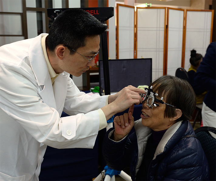 Optometrist James Chuang carefully checks a patient's eyesight