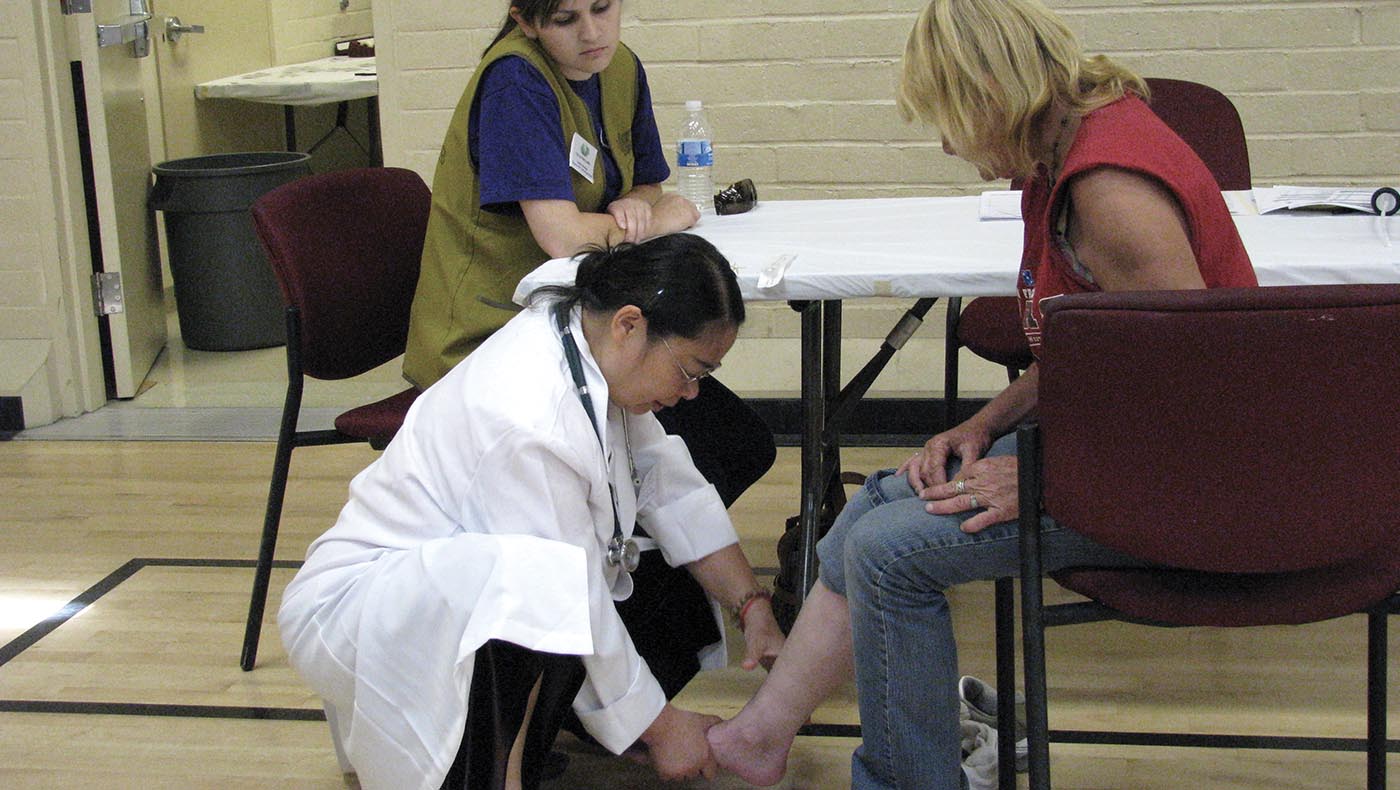 2009年7月26日，余素澄中醫師體貼地蹲下來為低收入病患檢查病情。攝影／陳碧惠