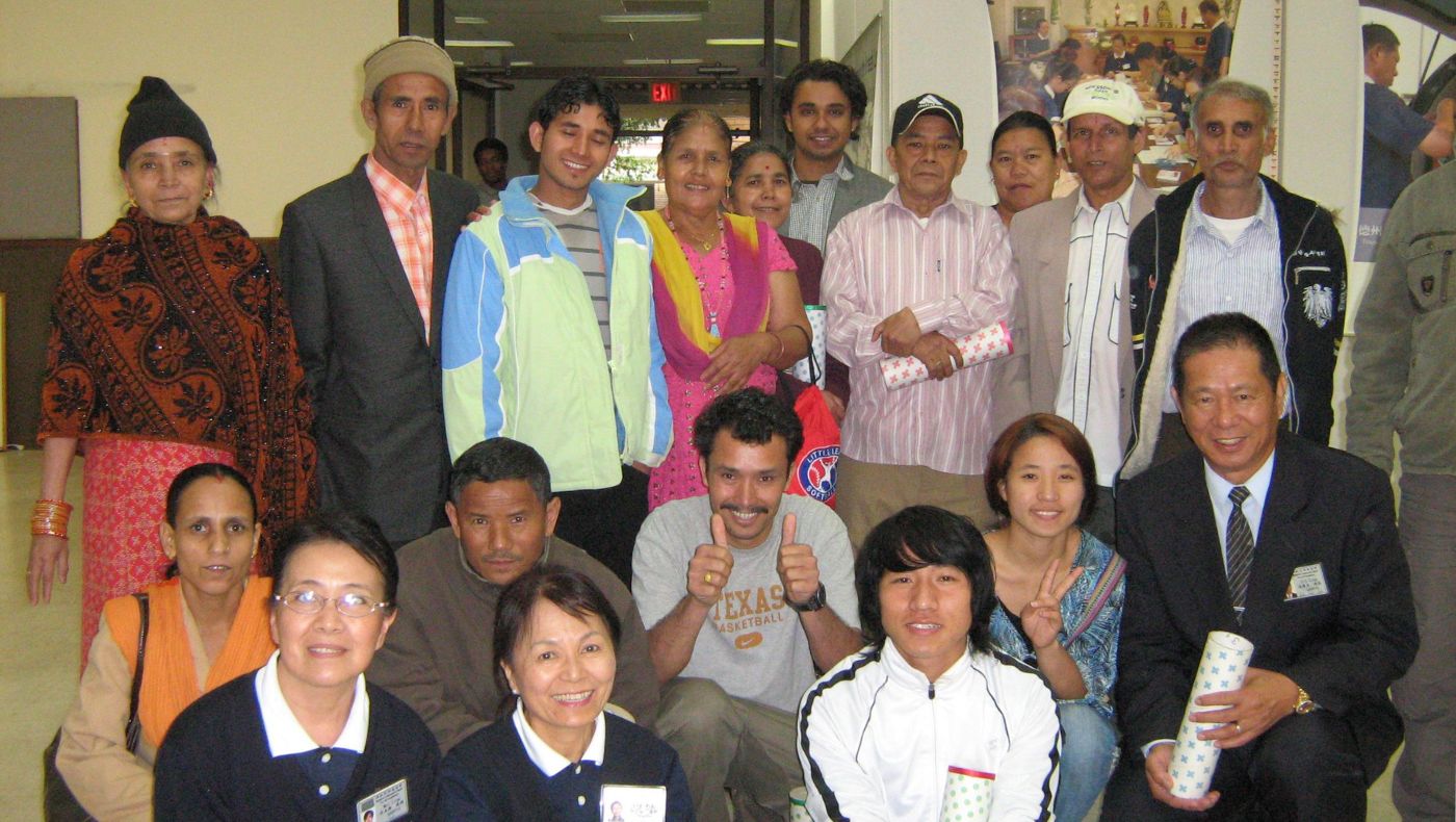 Current Executive Director of Tzu Chi USA’s Central Region, Yuanliang Ling (kneeling, right) and volunteer Rosa Miao (front row second left) pose with Bhutanese refugees