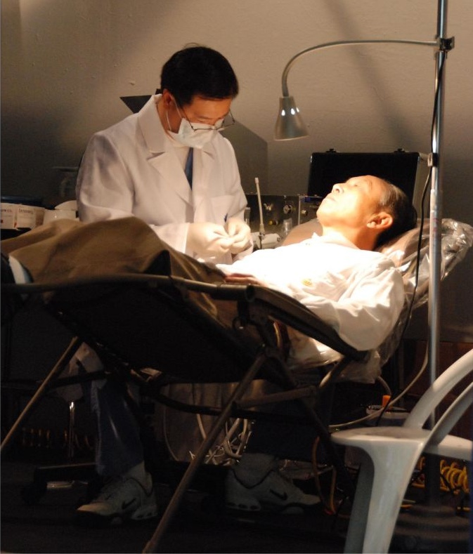 Dr. Long Su (left) examines a patient’s teeth during a joint clinic with the Texas Chinese Physicians Association