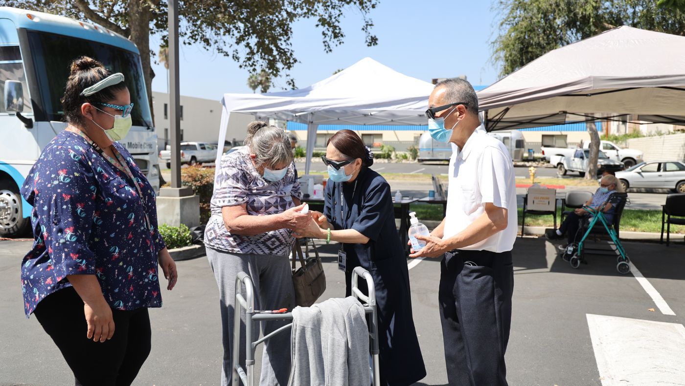 Tzu Chi volunteers from the American General Association cooperated with the Pacific Clinic. The volunteers drove the Ophthalmology Medical Love Medical Tour Vehicle to serve the public in front of the Pacific Clinic. Picture: Senior Brother William Keh (Jishe, 1st from right) and Senior Sister Mary Keh (Cixi, 2nd from right) presented hand sanitizer to the public.