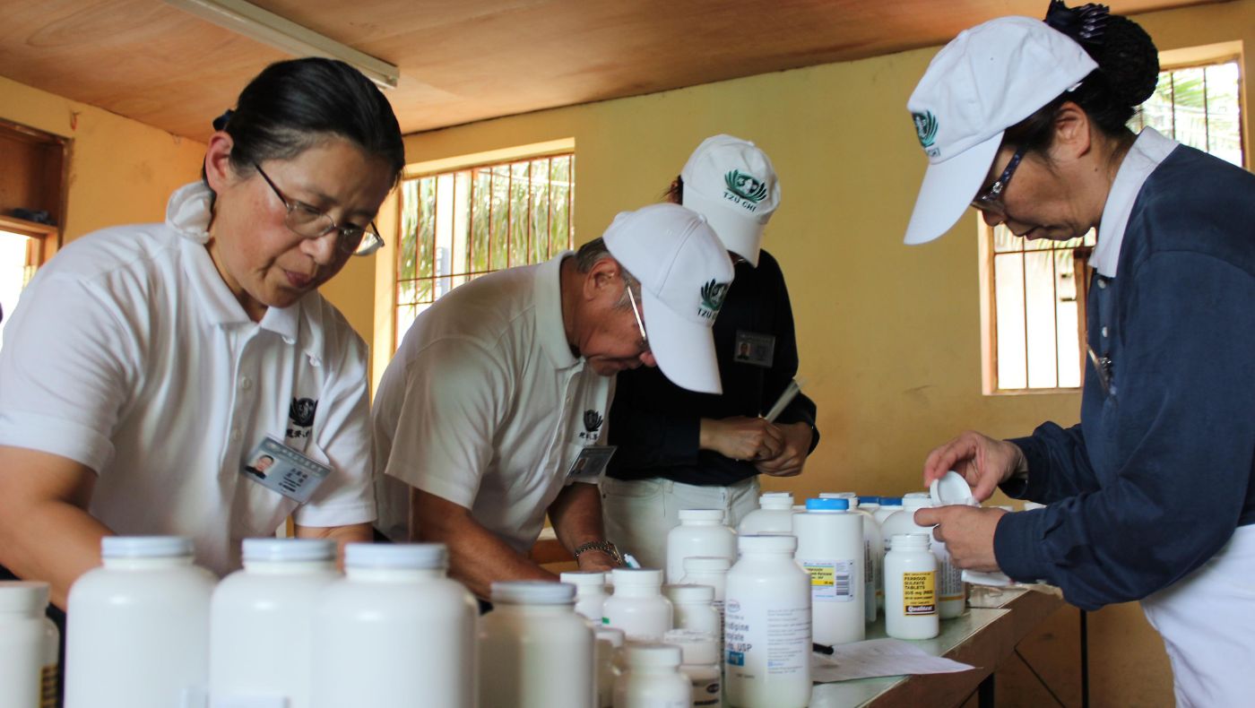 In October 2013, Tzu Chi held a rice distribution and free clinic event in Port-au-Prince, Haiti. Yuaner Wu (first from left) dispenses medicine.