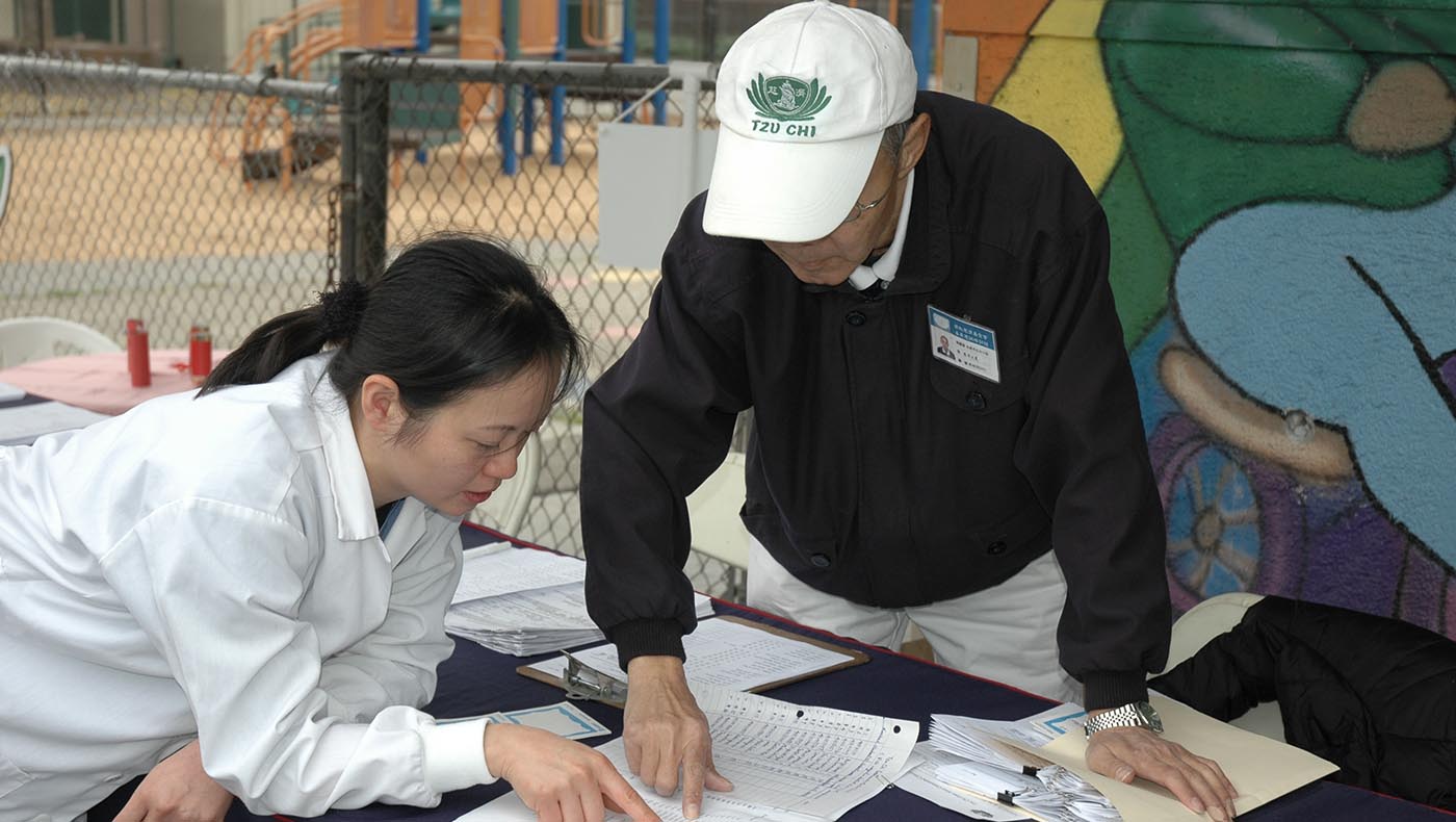 Dr. Chinghsin Wong (left) and general affairs volunteer Wenhsien Sun discuss the free clinic service on-site at Harry Slonaker Academy in 2009.