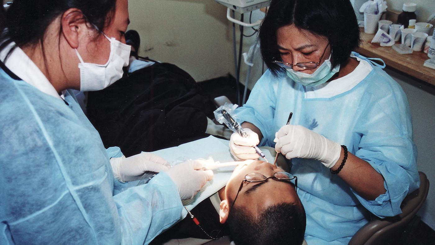 2001年七月，林美秋（右）參加萬佛聖城義診，為法師們簡單清洗、拋光牙齒。圖片來源／慈濟北加州分會