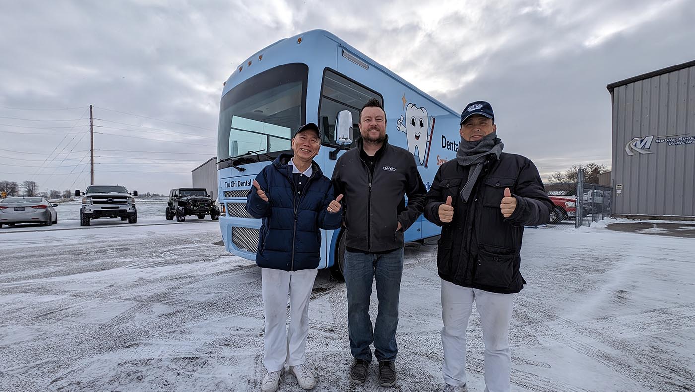 Tzu Chi USA Northeast Region volunteers Jinghua Chen (left) and Yanping Gong (right) take a photo with Corie Rayman (middle), Deputy Director of Operations at the factory that manufactured the new Tzu Chi Dental Mobile Clinic vehicle. The two volunteers spent a day traveling 710 miles to Indiana to pick it up, then drove another day to get back to New York.