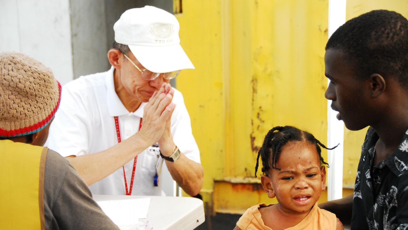 After the earthquake in Haiti in 2010, Tzu Chi arrived in the disaster area to provide assistance. Dr. Hiro Huang and fellow practitioner Dr. Joan Huang served the victims at a free clinic. The picture shows pediatrician Hiro Huang treating a child with systemic skin infection caused by poor environmental hygiene under high temperatures.