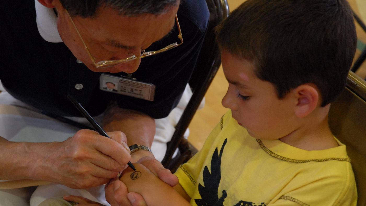 When treating children, Dr. Hiro Huang often draws cute cartoon characters on the children's hands to calm the nervous emotions of the young patients. The picture shows Dr. Huang drawing cute cartoons on the hands of young patients during a free clinic at the Disaster Relief Center in Suffolk, VA in 2008.