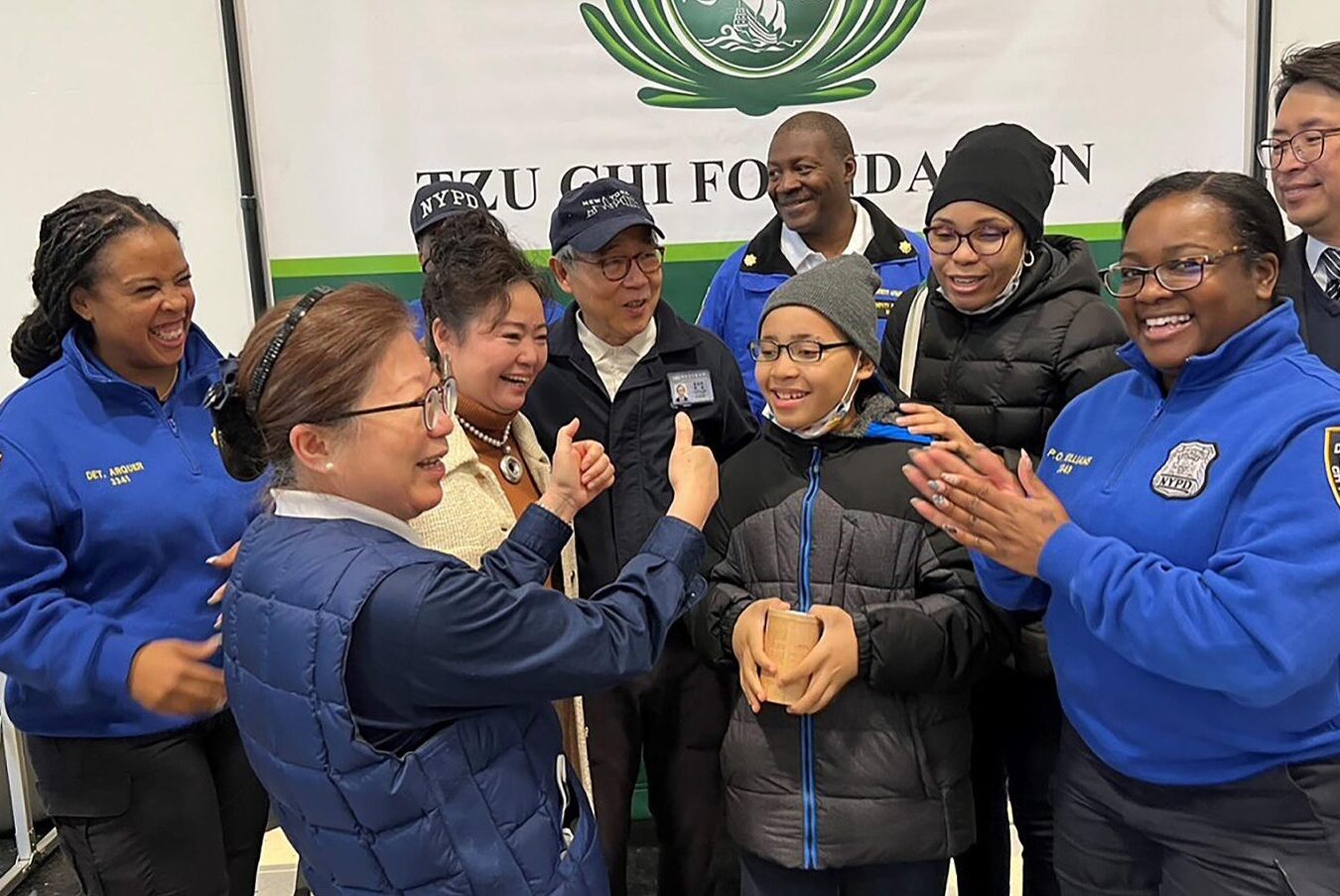 Tzu Chi volunteers and NYPD police officers congratulate Carlisle Ward on his new glasses