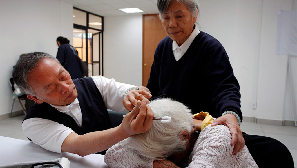 Chinese medicine practitioner Gao Zhongcheng (first from left) performs acupuncture on an old woman