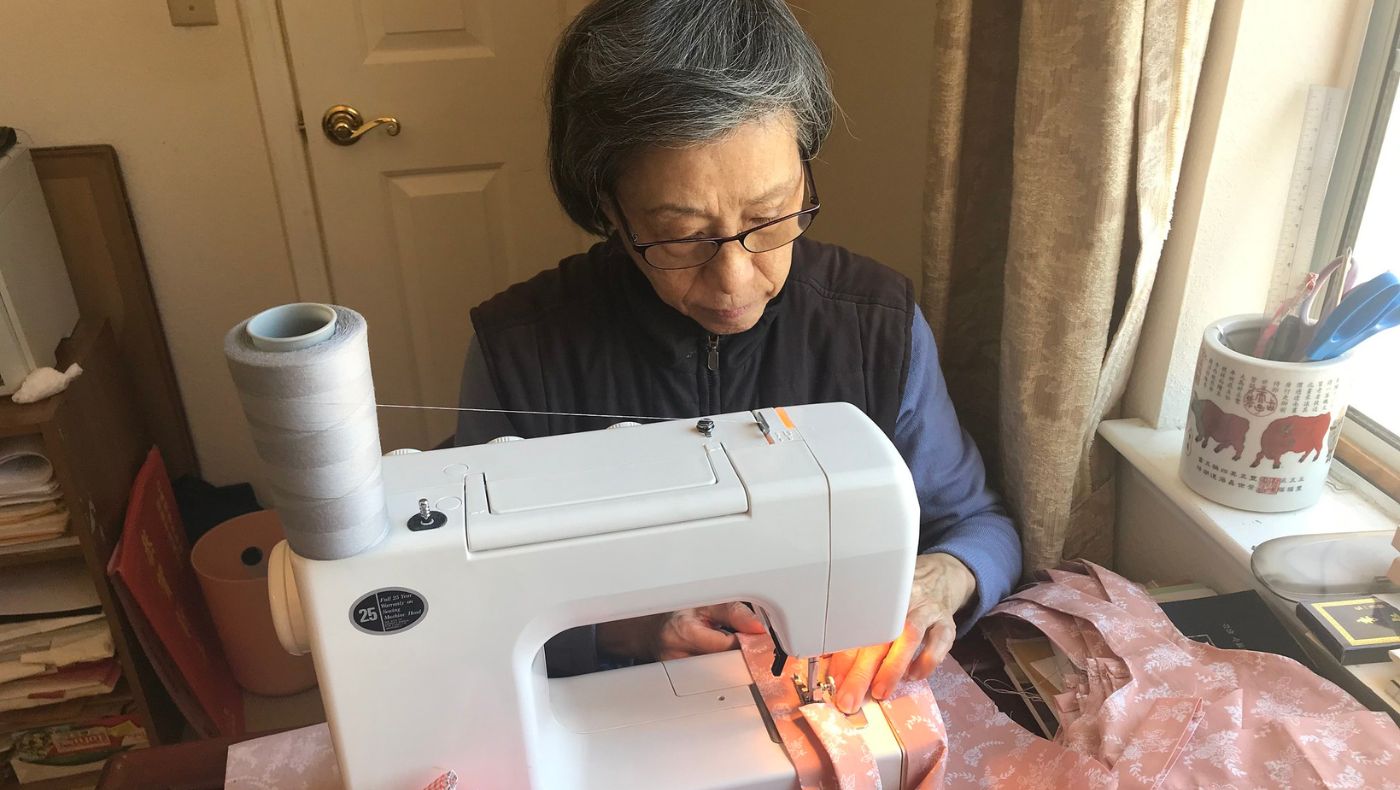 Huang Anqiong, an elderly volunteer from Northern California, cannot go out due to the epidemic, but she still helps sew hair caps for medical staff at home.