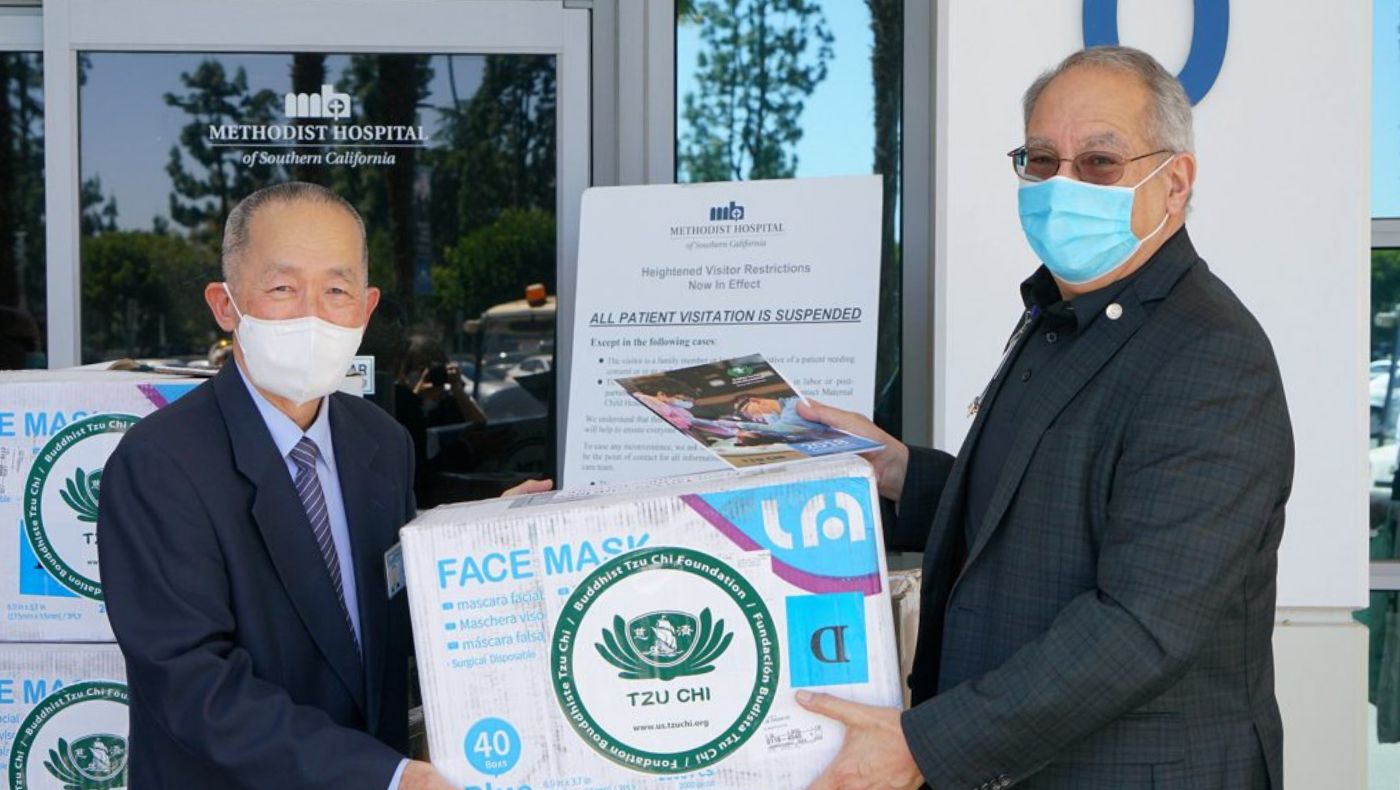Gezishe (left) delivers vegetarian lunch boxes and epidemic prevention materials to Mike Driebe, President of the Methodist Hospital Foundation.
