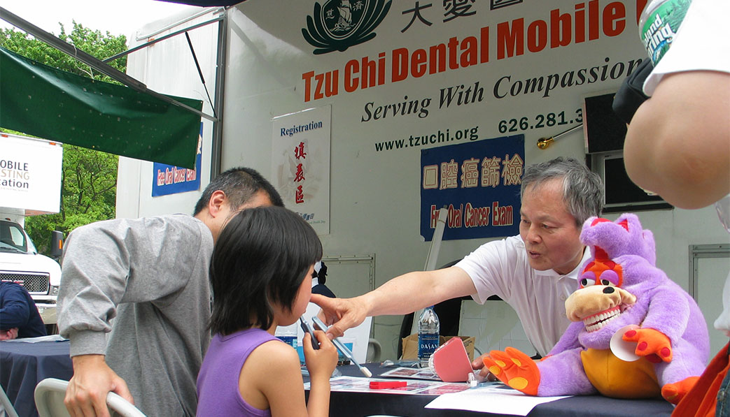 Dr. Zuolong Hsu (first right) shows children how to properly brush their teeth and advocates oral health education