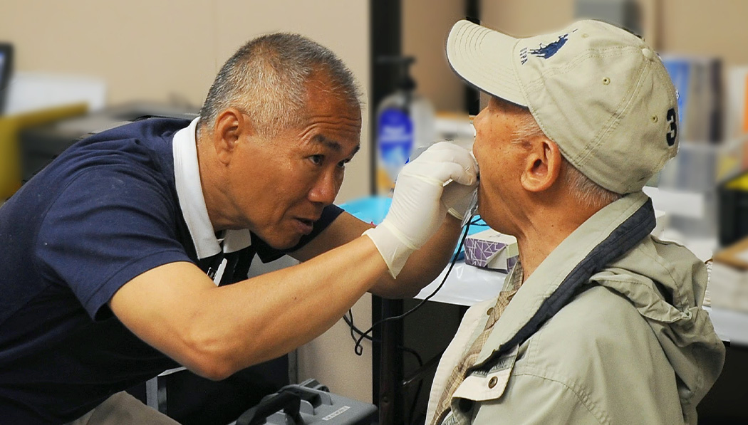Chenwei Hsu prepares a patient for an X-ray at a free dental event in June 2013.