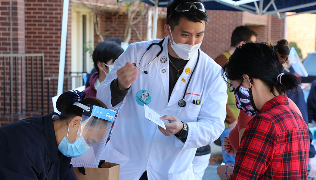 Dr. LamSon Nguyen collaborates with Tzu Chi volunteers to offer groceries to families in front of his pediatric practice in Seven Corners, Virginia.
