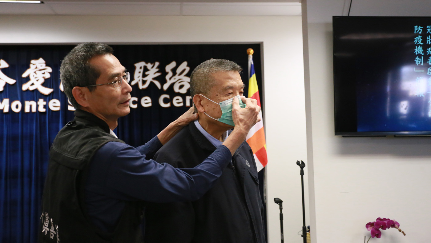 Tzu Chi volunteer Yuanhsiao Cheng (left) demonstrates the correct way to wear a mask.