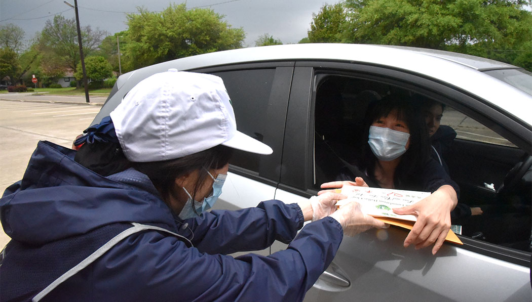 A parent of a Tzu Chi Academy student in Dallas, Texas, receives a pack of PPE with relief in April 2020.