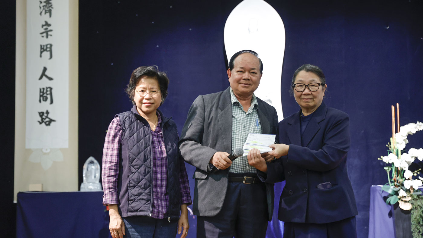 Tzu Chi USA CEO Debra Boudreaux accepts a donation on behalf of the foundation from Reggie Shum and his wife. Photo/Shuli Lo