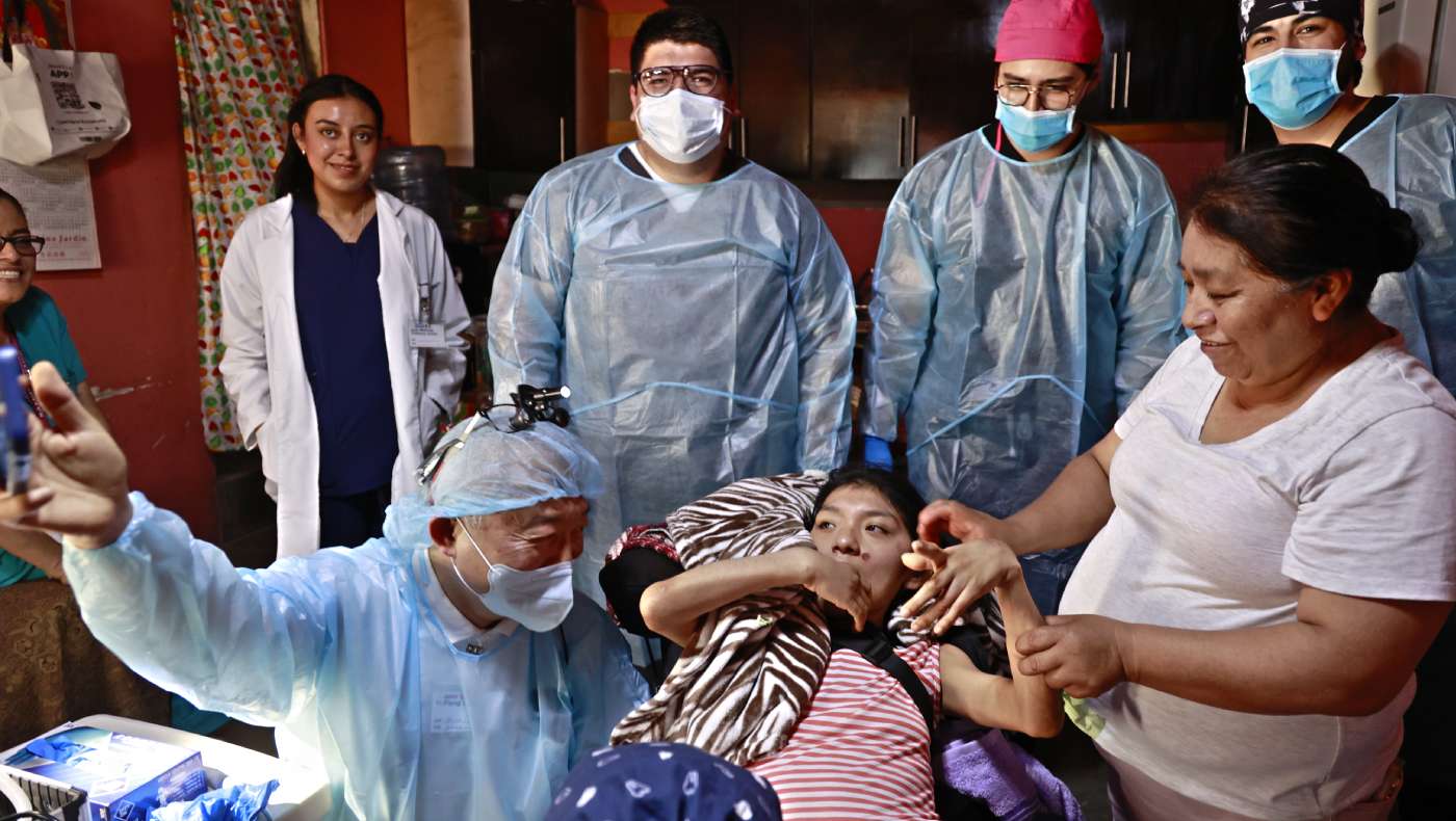 El Dr. Yi Pang Lee muestra a la paciente su estado dental con imágenes tomadas con su teléfono móvil, la tranquiliza con paciencia y le explica el proceso del tratamiento. Junto a ellos están la madre de la paciente y el equipo médico. Foto/ Shuli Lo