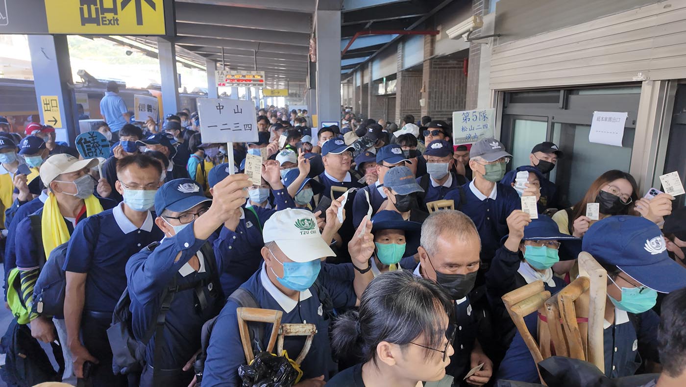 災區光復鄉的車站站滿了從全台各地來支援的民眾，大家將車票高舉過頭頂，等待檢票出站。在人潮中，可見藍天白雲的身影。攝影／蔡麗瑜