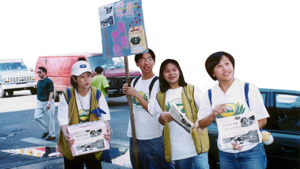 Four Tzu Chi volunteers stand together on a street fundraising.