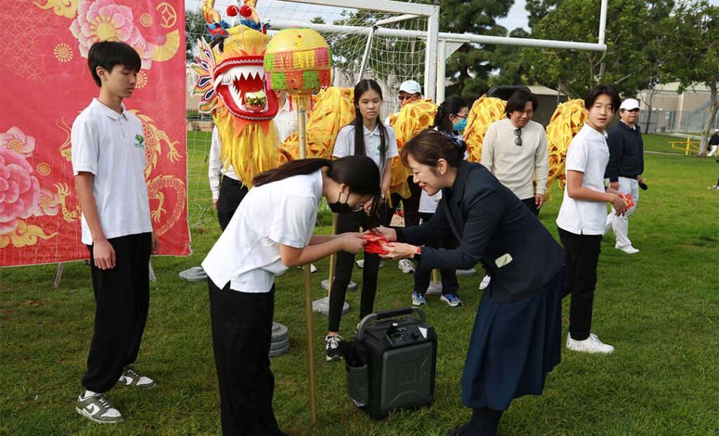 Chingchuan Shih distributes traditional red envelopes symbolizing blessings and good fortune to students