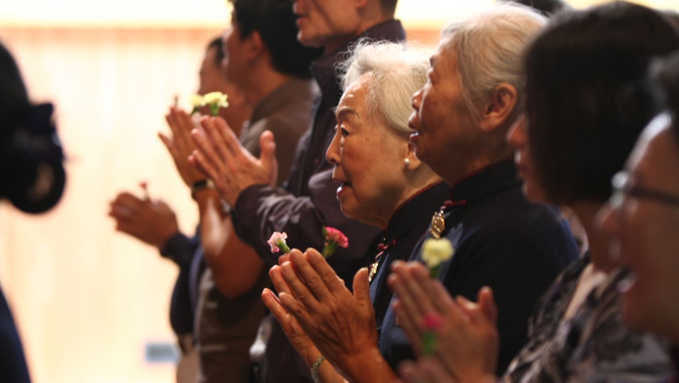At Tzu Chi USA’s Greater Washington D.C. Region Office in Reston, Virginia, volunteers and community members join palms as livestreamed prayers from Taiwan fill the hall. Photo/Benny Cheng